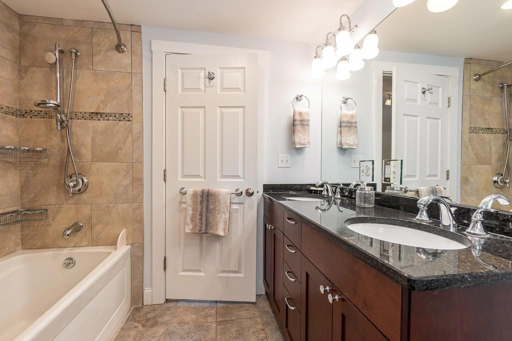 24 Wheeler Road Bolton, MA 01740 - Photo 19 of 28 a bathroom with a granite countertop double vanity sink a mirror a bathtub and shower