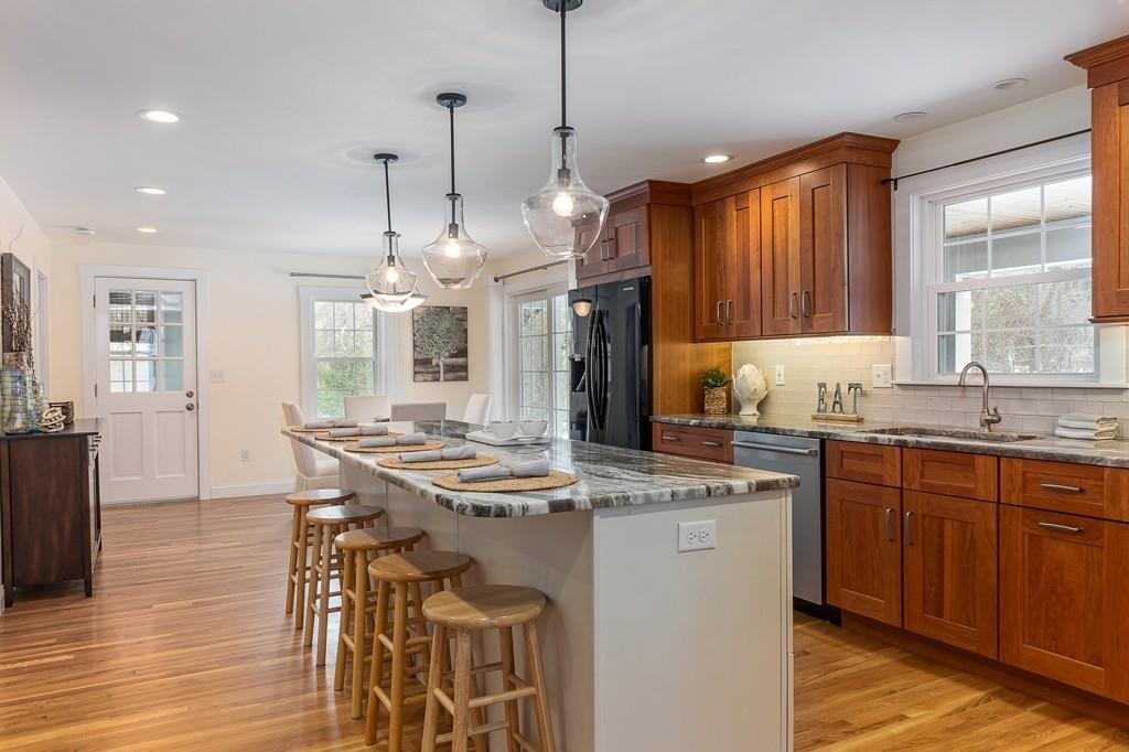24 Wheeler Road Bolton, MA 01740 - Photo 4 of 28 a kitchen with stainless steel appliances granite countertop a stove a sink dishwasher a refrigerator and a dining table with wooden floor