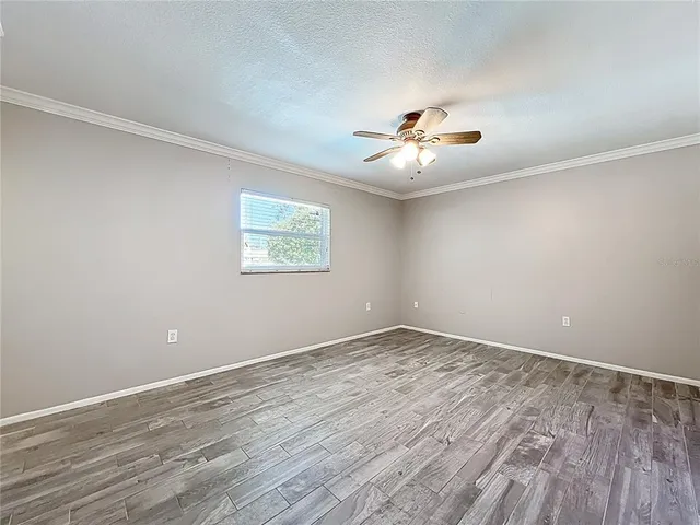 a view of an empty room with a window and wooden floor