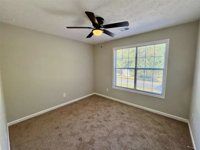 a view of an empty room with a ceiling fan and window