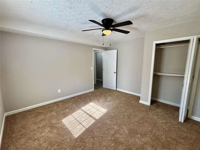 a view of empty room with wooden floor and ceiling fan
