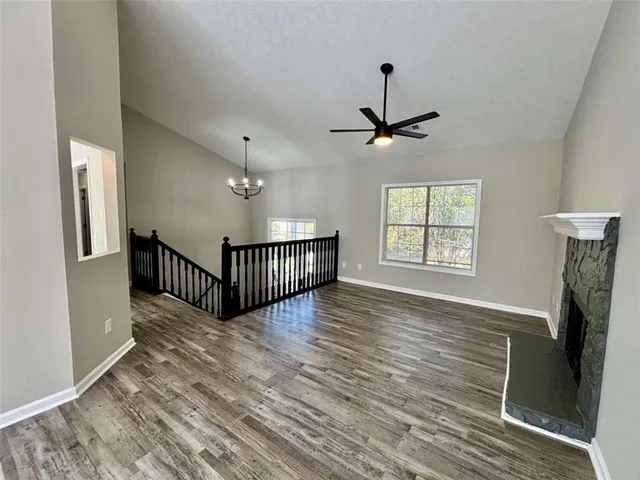 an empty room with wooden floor windows and a ceiling fan