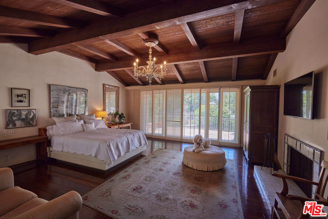 623 North Hillcrest Road Beverly Hills, CA 90210 - Photo 14 of 24 a spacious bedroom with a bed a couch and a ceiling fan