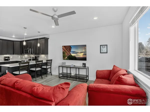 a living room with furniture kitchen view and a large window