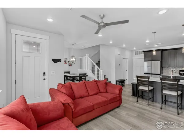 a living room with furniture a wooden floor and a ceiling fan
