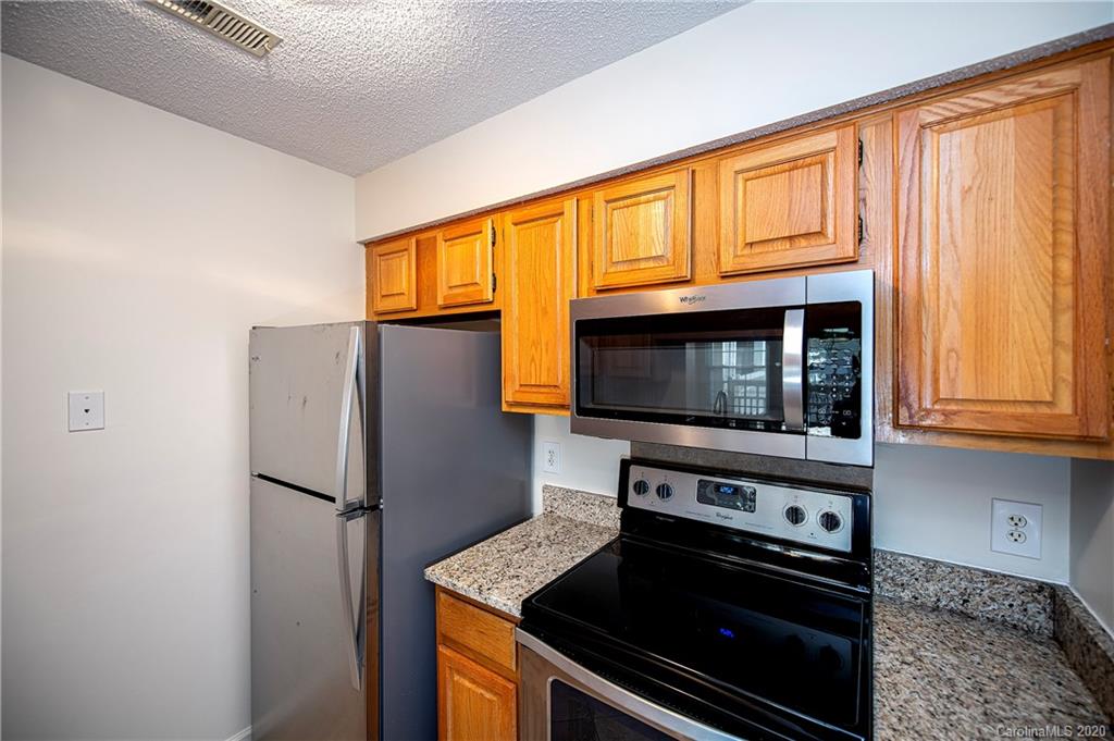 5003 Sharon Road, Unit R Charlotte, NC 28210 - Photo 9 of 23 a kitchen with stainless steel appliances granite countertop a refrigerator stove and microwave