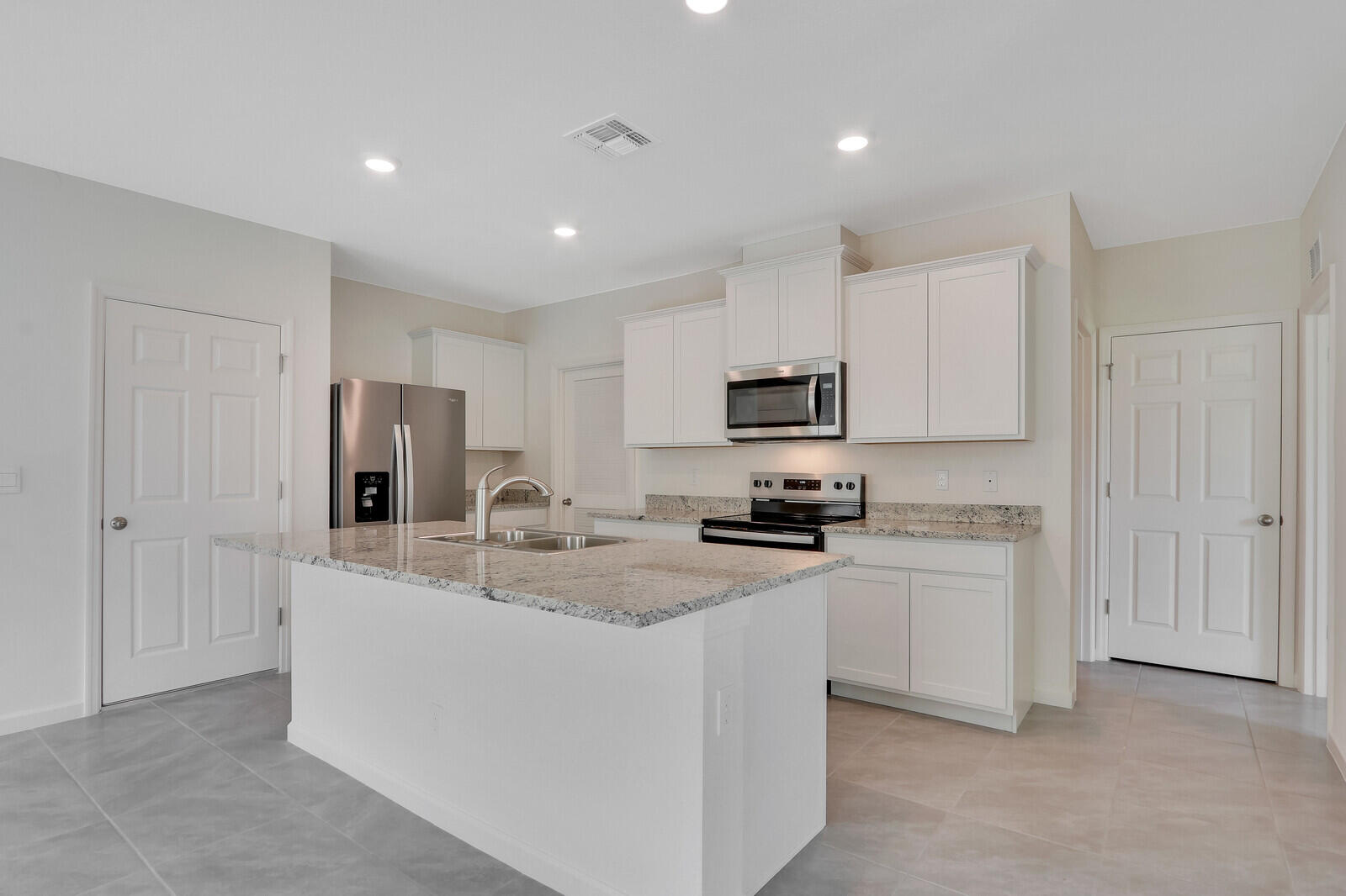 12335 Southwest Nettuno Way Port Port St. Lucie, FL 34987 - Photo 11 of 33 a kitchen with stainless steel appliances granite countertop a stove a sink a refrigerator a microwave and cabinets