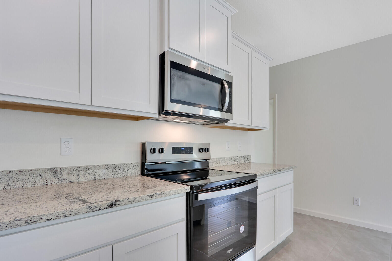 12335 Southwest Nettuno Way Port Port St. Lucie, FL 34987 - Photo 13 of 33 a kitchen with stainless steel appliances granite countertop white cabinets and a stove top oven with granite countertops