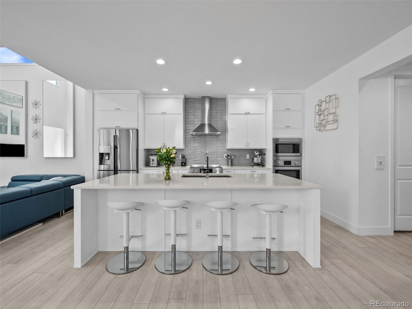 a large white kitchen with lots of counter space and stainless steel appliances