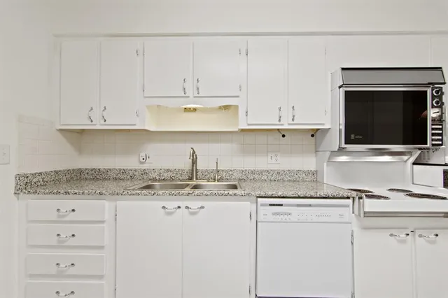 a kitchen with granite countertop white cabinets and white appliances