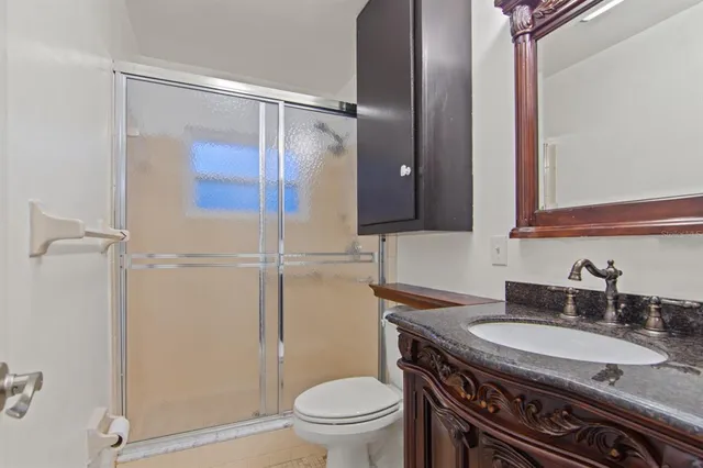 a bathroom with a granite countertop sink toilet and shower