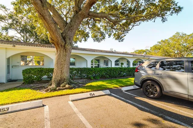 a view of a car parked in front of a house with a large tree