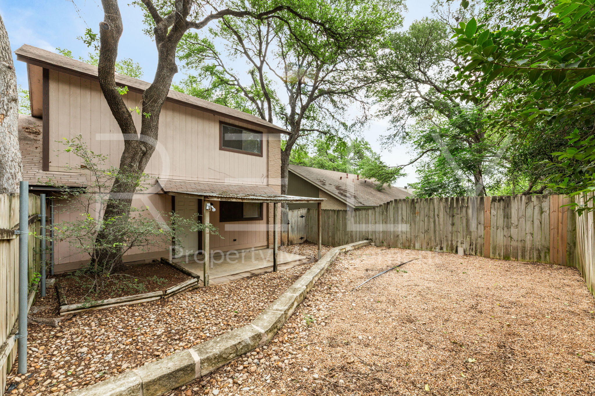 1005 Milford Way, Unit A Austin, TX 78745 - Photo 30 of 30 a backyard of a house with large trees and wooden fence