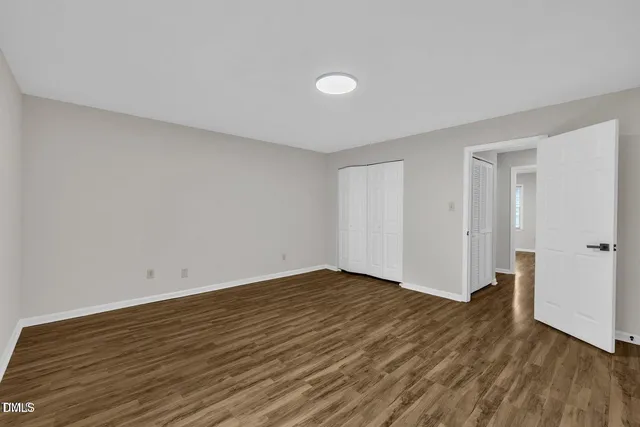 a view of an empty room with wooden floor and closet