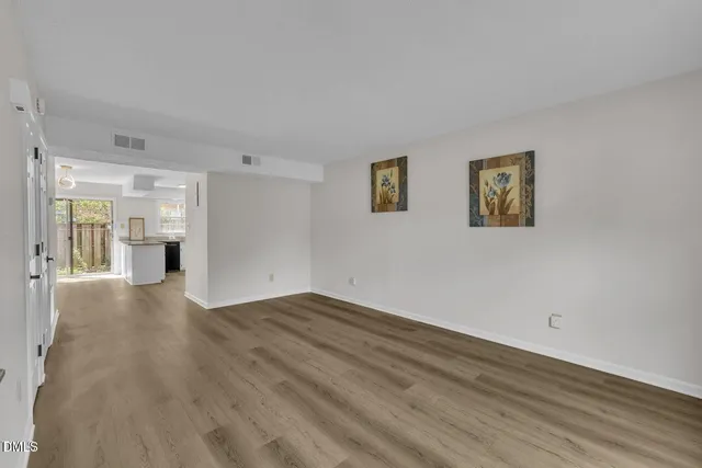 a view of empty room with wooden floor and window