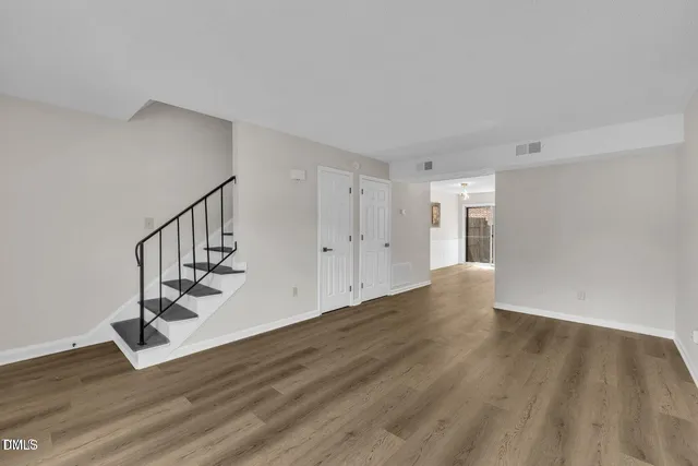 a view of an empty room with wooden floor and stairs