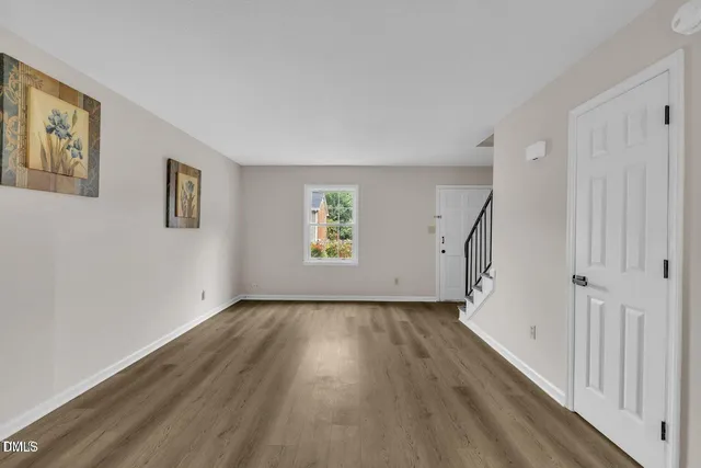 a view of an empty room with a window and wooden floor