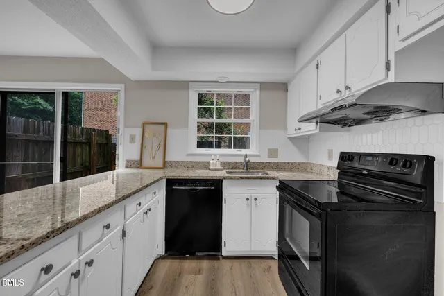 a kitchen with granite countertop a sink stove and cabinets