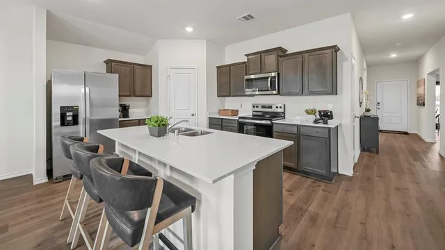 a kitchen with kitchen island a stove a table and chairs in it