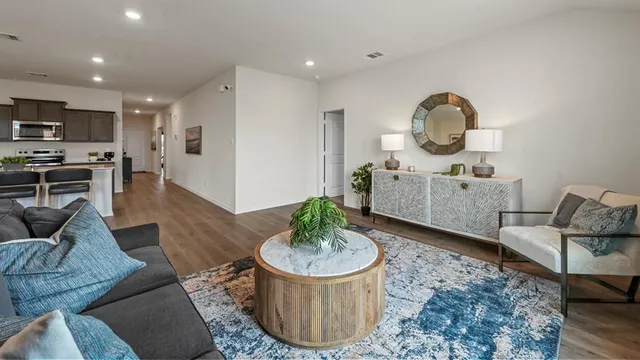 a living room with furniture a rug and kitchen view