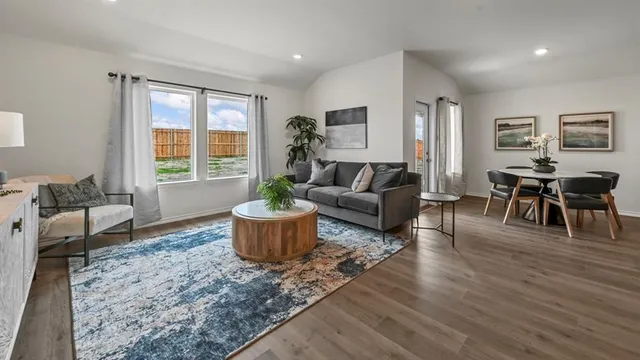 a living room with furniture a dining table and a large window
