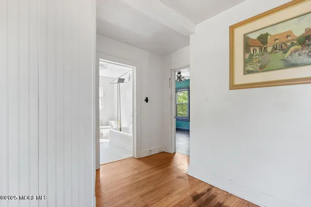 a view of an empty room with wooden floor and a bathroom