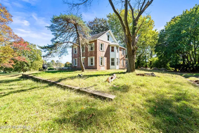 a view of a white house with a large tree and plants