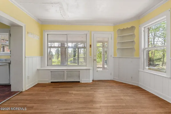 a view of an empty room with a window and wooden floor