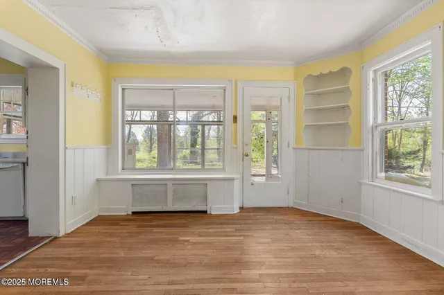 a view of an empty room with a window and wooden floor