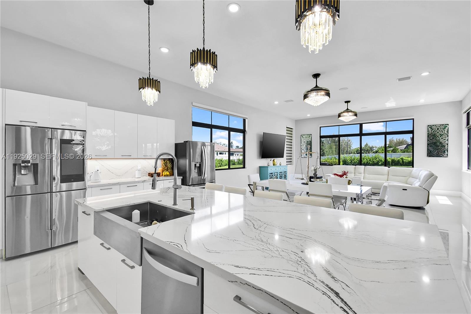 15846 Southwest 49th Street Southwest Ranches, FL 33331 - Photo 5 of 38 a kitchen with kitchen island a large counter top space a sink appliances and a chandelier