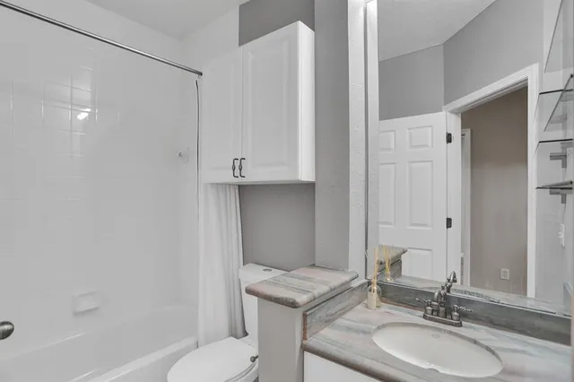 a bathroom with a granite countertop sink toilet a mirror and shower