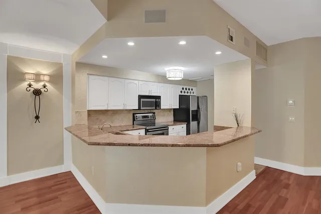 a kitchen with kitchen island a counter top space appliances and a view of living room