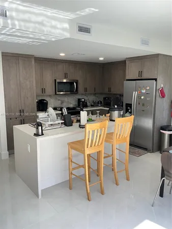 a kitchen with stainless steel appliances kitchen island granite countertop a table chairs microwave and sink