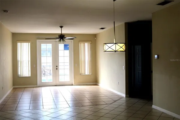 a view of an empty room with window and chandelier fan