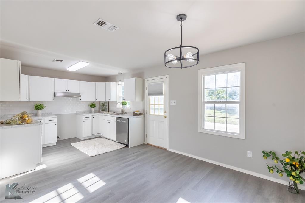 a kitchen with white cabinets and window