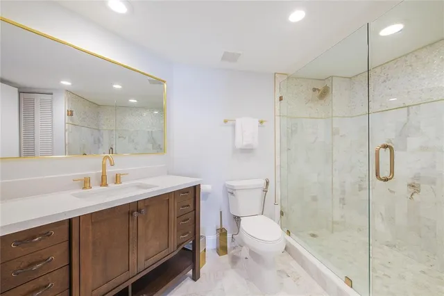 a bathroom with a granite countertop sink a toilet and shower