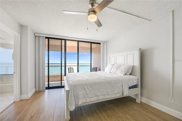 a bedroom with a bed and a large window with wooden floor