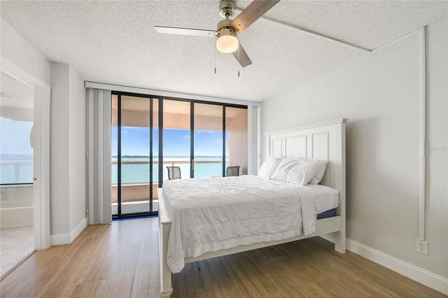 a bedroom with a bed and a large window with wooden floor