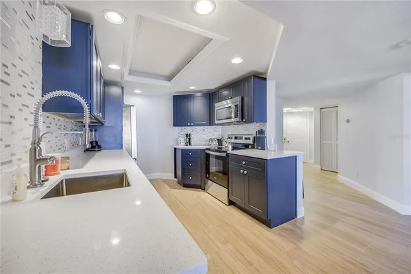 a large kitchen with stainless steel appliances a stove a sink a refrigerator and a wooden cabinets