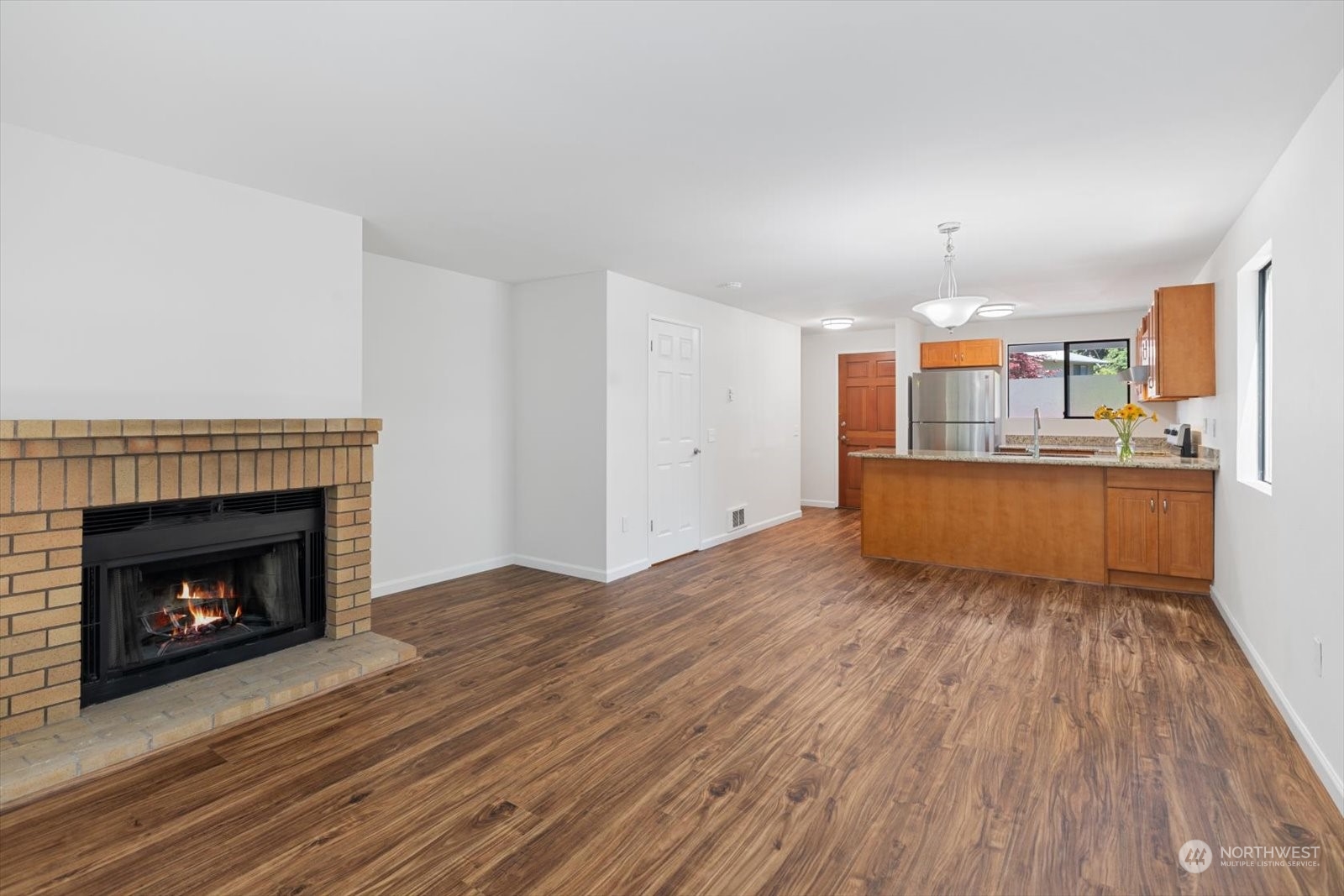 22906 Edmonds Way, Unit 9 Edmonds, WA 98020 - Photo 8 of 22 a view of a kitchen and an empty room with wooden floor a fireplace