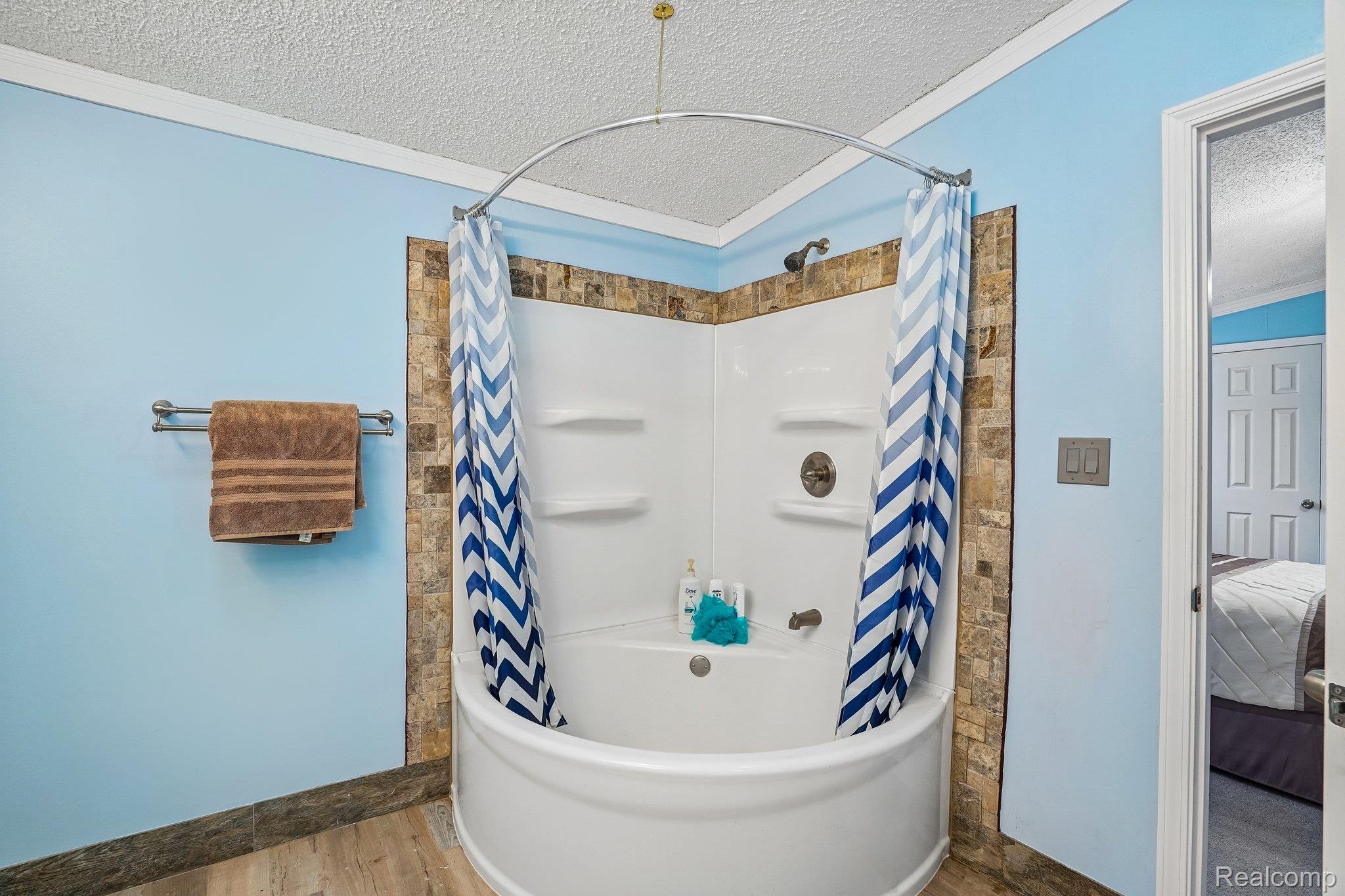3363 North Branch Road North Branch, MI 48461 - Photo 32 of 38 Bathroom featuring a textured ceiling, crown molding, shower / bath combo with shower curtain, wood finished floors, and ensuite bath