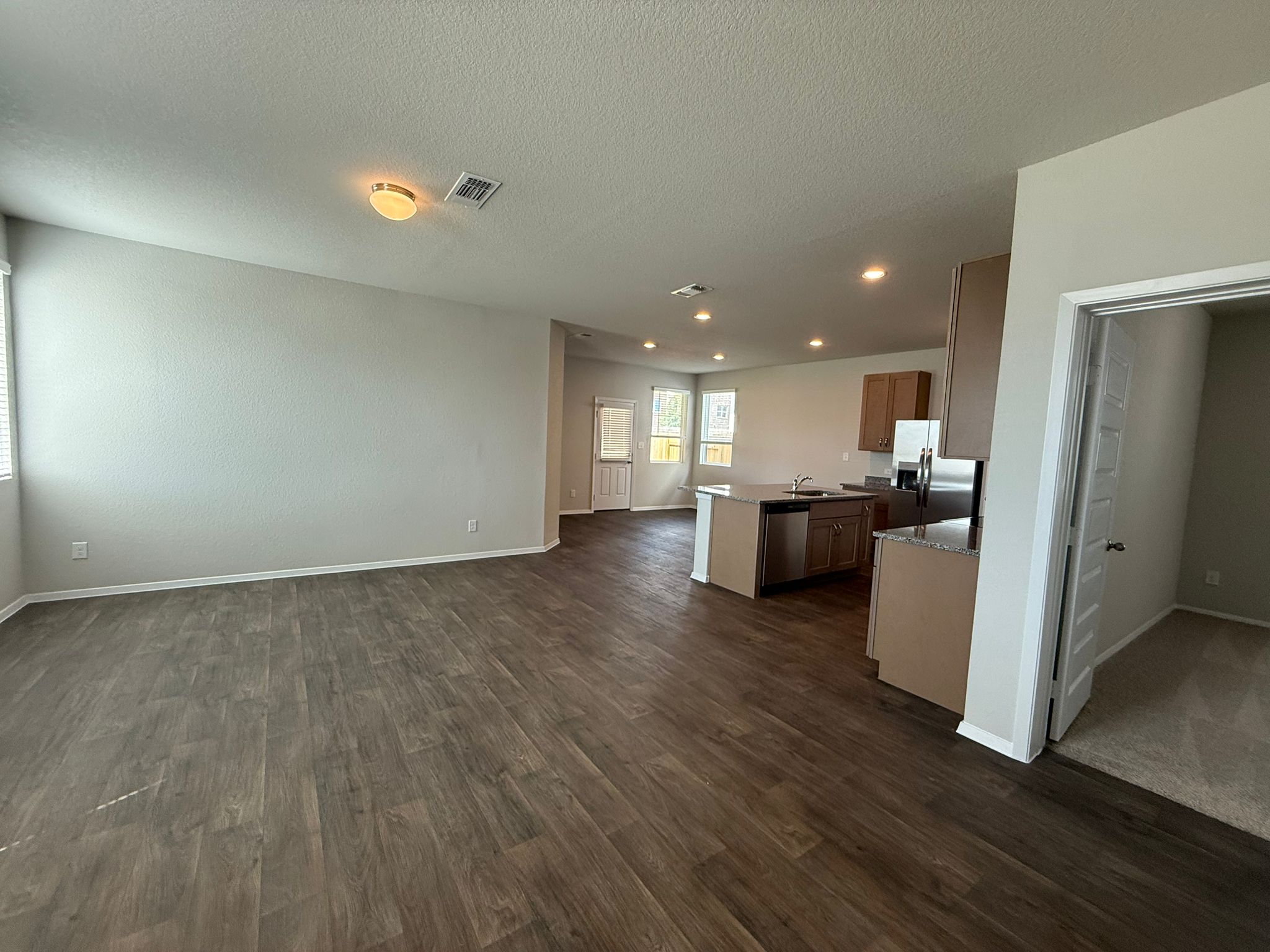 2713 Totley Road Manor, TX 78653 - Photo 39 of 40 Kitchen featuring appliances with stainless steel finishes, open floor plan, dark wood-style floors, a center island with sink, and recessed lighting
