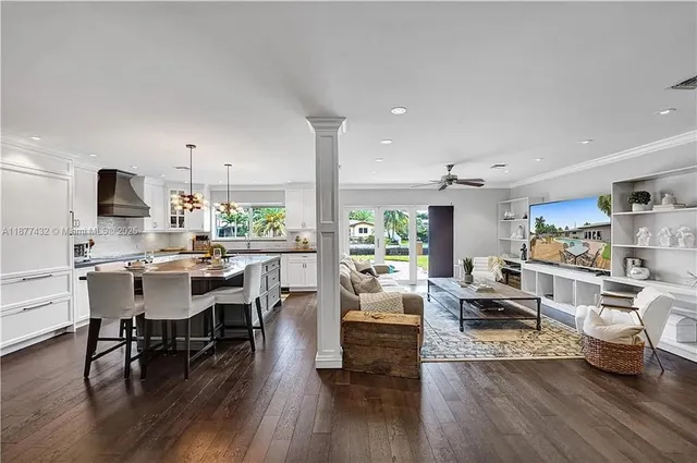 a living room with stainless steel appliances kitchen island granite countertop wooden floor a couch and a view of kitchen