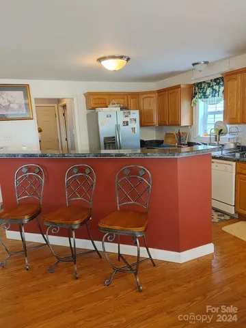 a kitchen with stainless steel appliances granite countertop a table chairs in it and wooden floors