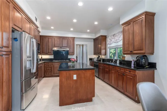 a kitchen with stainless steel appliances granite countertop a refrigerator and a stove top oven