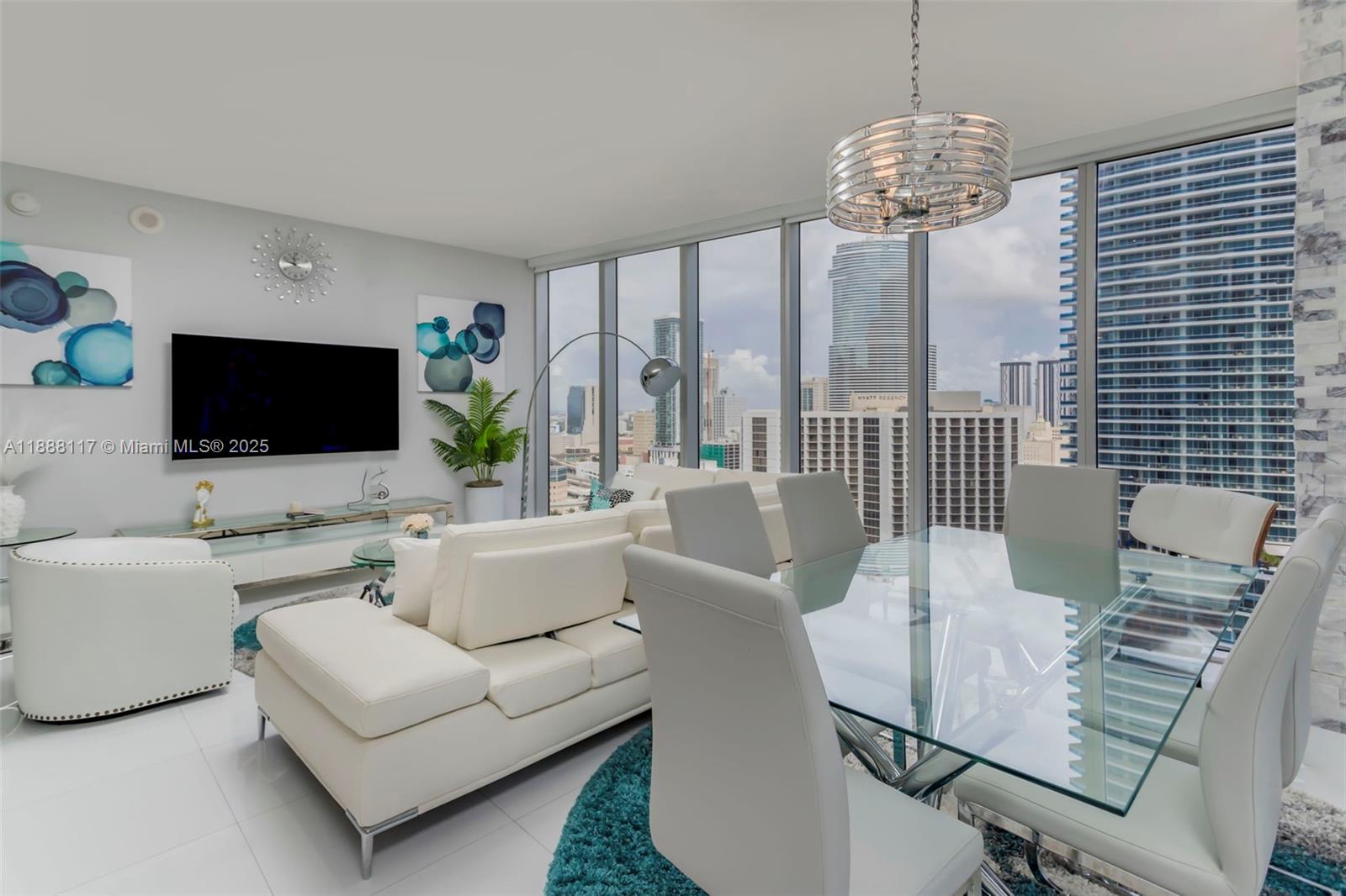 485 Brickell Avenue, Unit 2502 Miami, FL 33131 - Photo 4 of 24 a living room with furniture a flat screen tv and a chandelier