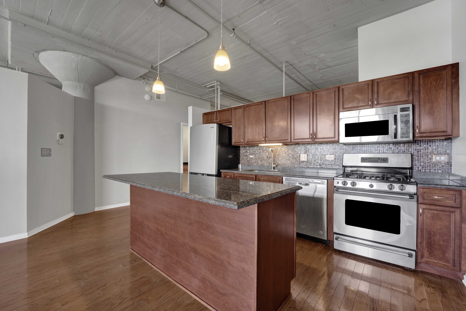 1525 South Sangamon Street, Unit 504 Chicago, IL 60608 - Photo 5 of 32 a kitchen with stainless steel appliances granite countertop a stove a sink and a microwave