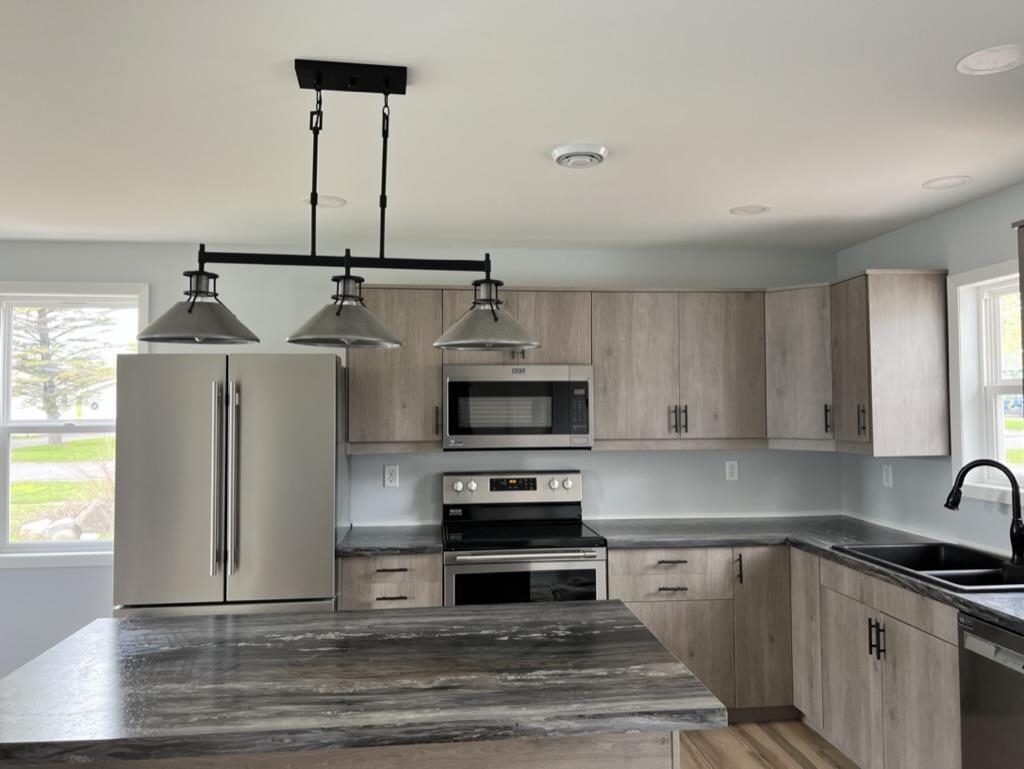 35 Field Road Silver Bay, MN 55614 - Photo 4 of 20 Kitchen featuring stainless steel appliances, light brown cabinetry, pendant lighting, light wood-type flooring, and dark stone countertops