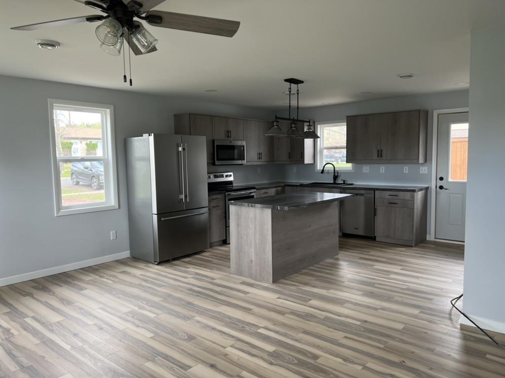 35 Field Road Silver Bay, MN 55614 - Photo 6 of 20 Kitchen featuring appliances with stainless steel finishes, pendant lighting, light wood finished floors, a ceiling fan, and a center island
