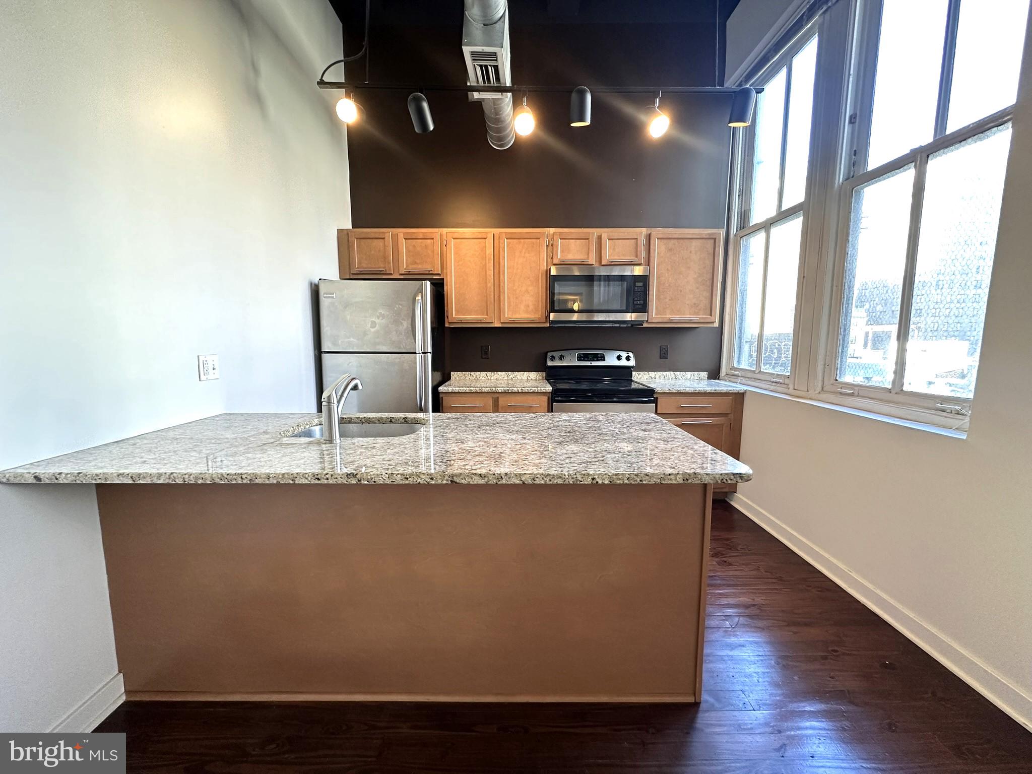 1510 Chestnut Street, Unit 902 Philadelphia, PA 19102 - Photo 7 of 19 a kitchen with kitchen island stainless steel appliances a sink stove and a window